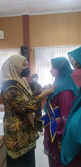 foto bunda paud kota bukittinggi sedang memasang pin kepada bunda paud kec